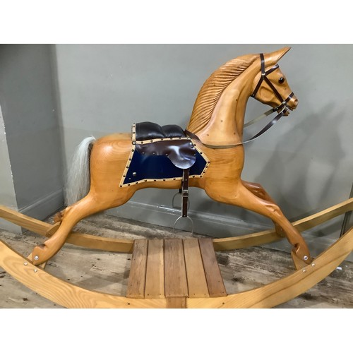 472 - A rocking horse in beech, carved mane, leather reins and saddle and on bow rocker