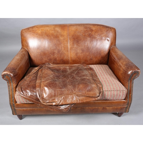 57 - A brown leather close-nailed two seater sofa in the 1920s style, having two cushion seat with interc... 