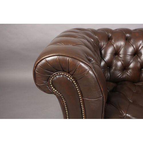 129 - A dark brown buttoned leather back Chesterfield club chair with close nail studding, on front bun fe... 