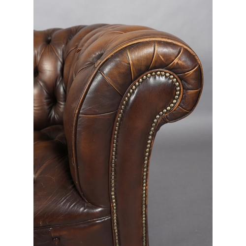 130 - A brown buttoned leather back Chesterfield sofa with close nail studding, on front bun feet with con... 