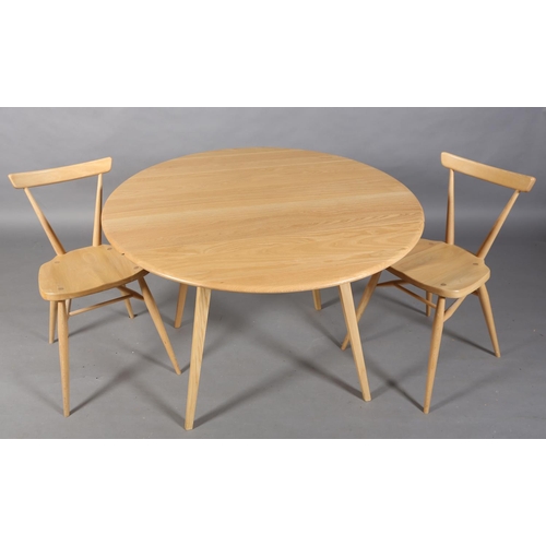 35 - A modern Ercol beech circular drop leaf dining table, on square tapered splayed legs together with a... 