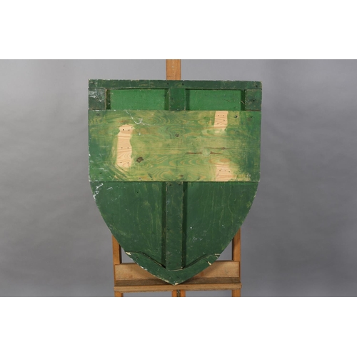 164 - A shield shaped wooden plaque painted with a red dragon on a green ground, 74cm x 63cm