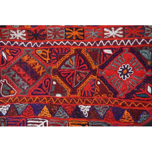 103 - An embroidered Kelim rug probably Afghanistan, the red ground, hand worked in orange, blue, teal, bu... 