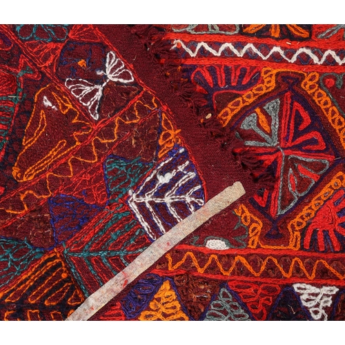 103 - An embroidered Kelim rug probably Afghanistan, the red ground, hand worked in orange, blue, teal, bu... 