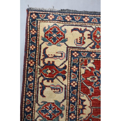 104 - A Caucasian rug, the fox red field filled with plant forms in ivory and blue, with conforming princi... 