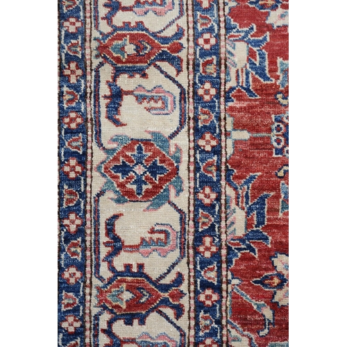 104 - A Caucasian rug, the fox red field filled with plant forms in ivory and blue, with conforming princi... 