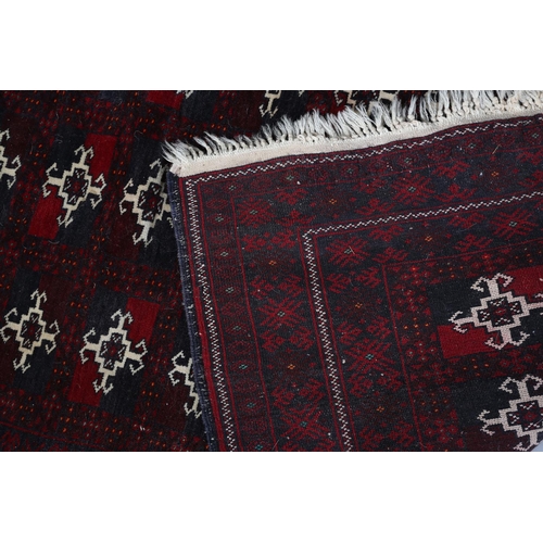 105 - A Bokhara rug of deep aubergine, ivory and blue, the field filled with three rows of ten small medal... 