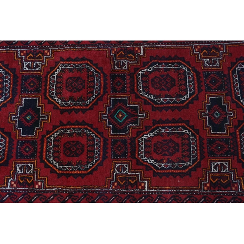 106 - A Bokhara rug, the wine field filled with two rows of four medallions in orange, white and black, pr... 