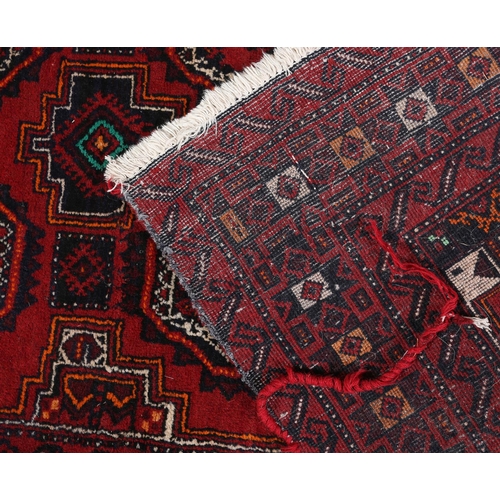 106 - A Bokhara rug, the wine field filled with two rows of four medallions in orange, white and black, pr... 