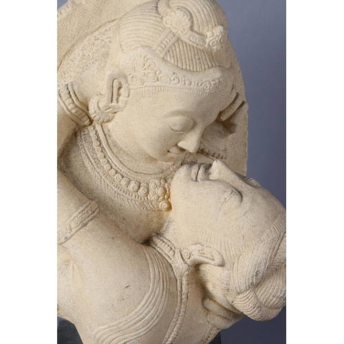 64 - An Indian Hindu carved sandstone bust of Shiva Kissing Parvati on ebonised wood plinth, 46cm high