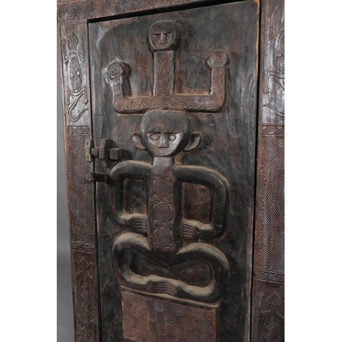 110 - An African inspired dark wood single door cupboard, having a wavy pediment, carved with two birds ab... 