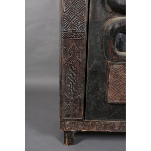 110 - An African inspired dark wood single door cupboard, having a wavy pediment, carved with two birds ab... 