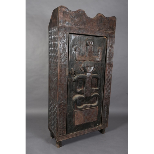 110 - An African inspired dark wood single door cupboard, having a wavy pediment, carved with two birds ab... 