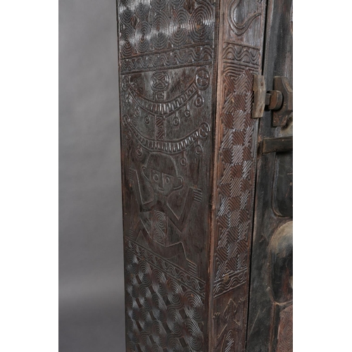 110 - An African inspired dark wood single door cupboard, having a wavy pediment, carved with two birds ab... 