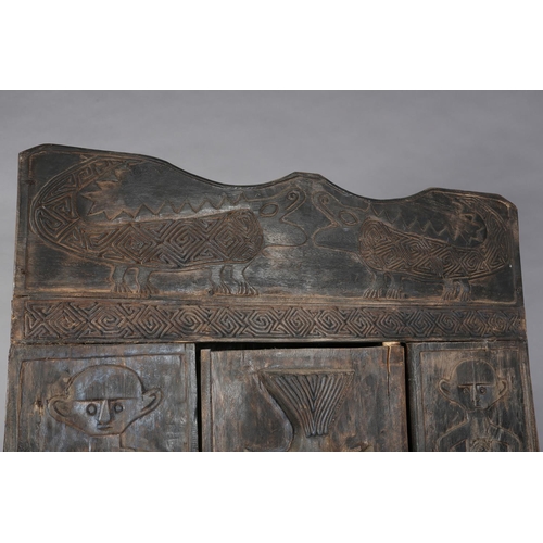 111 - An African inspired dark wood single door cupboard, having a wavy pediment carved with two crodiles ... 