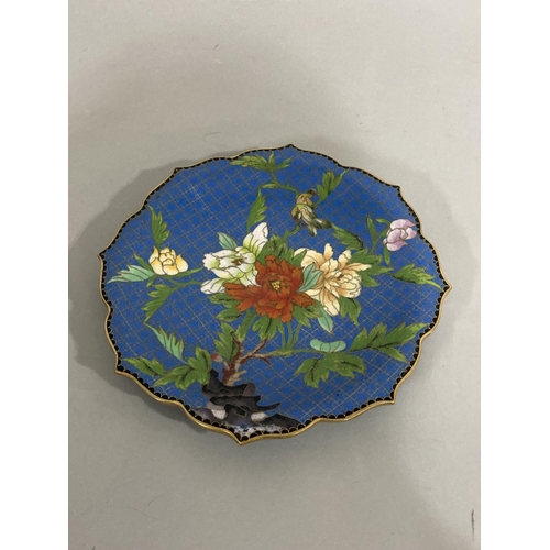 38 - A Chinese cloisonné plate of circular form and bracketed outline, decorated with rocks issuing, peon... 