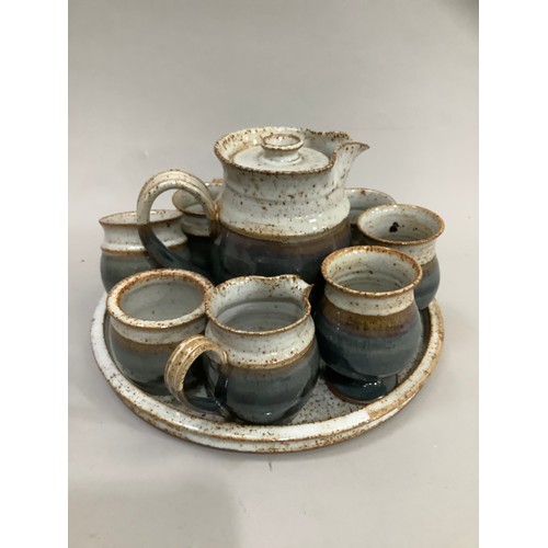 63 - A Studio Pottery coffee pot, sugar and cream, four mugs, two beakers and circular tray