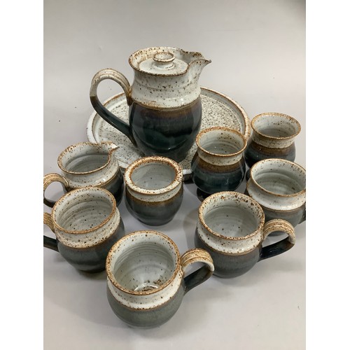 63 - A Studio Pottery coffee pot, sugar and cream, four mugs, two beakers and circular tray