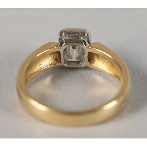 439 - A SINGLE STONE DIAMOND RING in 18ct yellow and white gold, the emerald cut stone collet set flanked ... 