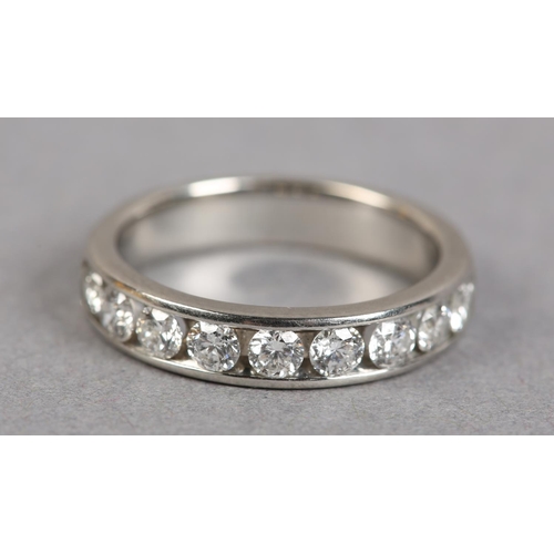 438 - A HALF HOOP DIAMOND RING IN PLATINUM, the brilliant cut stones channel set in line, finger size N 1/... 