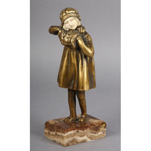 64 - AN ART DECO GILDED BRONZE AND IVORY, of a young girl dressed for the cold with cloche hat and muff, ... 