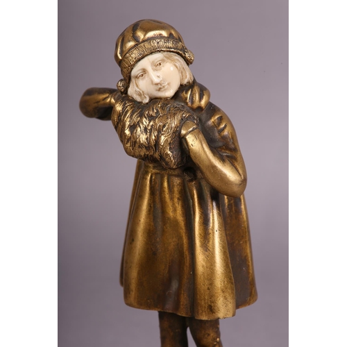 64 - AN ART DECO GILDED BRONZE AND IVORY, of a young girl dressed for the cold with cloche hat and muff, ... 