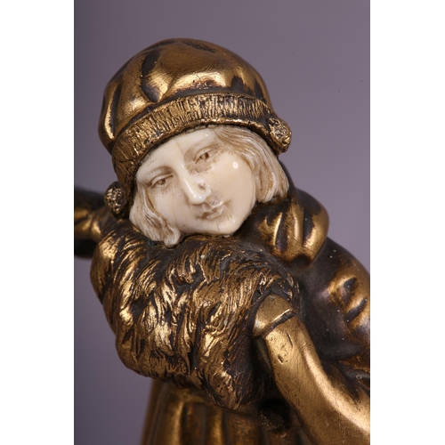 64 - AN ART DECO GILDED BRONZE AND IVORY, of a young girl dressed for the cold with cloche hat and muff, ... 