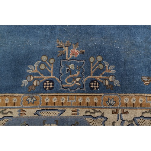 491 - AN ART DECO CHINOISSERIE CARPET, the blue field worked with plant forms, pagodas, butterflies, the p... 