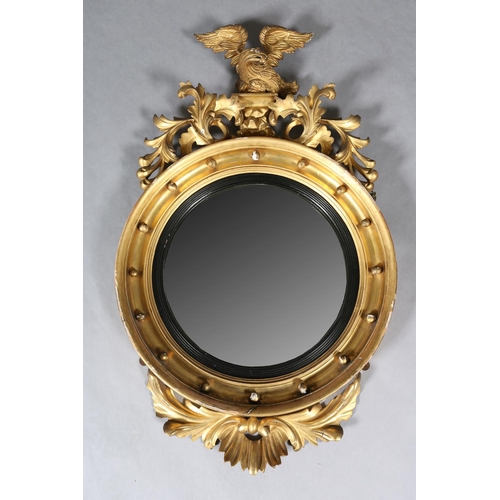 284 - A REGENCY GILT WOOD AND GESSO CONVEX WALL MIRROR, the circular frame applied with spheres and surmou... 