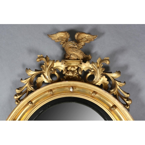 284 - A REGENCY GILT WOOD AND GESSO CONVEX WALL MIRROR, the circular frame applied with spheres and surmou... 
