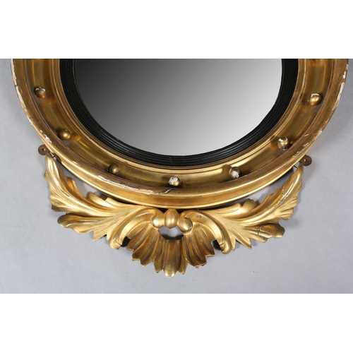 284 - A REGENCY GILT WOOD AND GESSO CONVEX WALL MIRROR, the circular frame applied with spheres and surmou... 