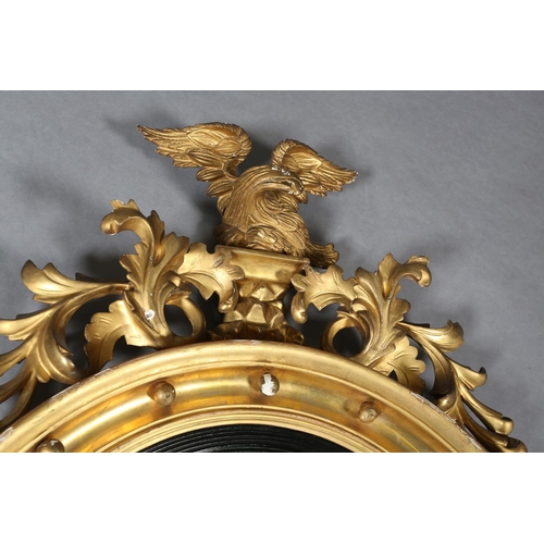 284 - A REGENCY GILT WOOD AND GESSO CONVEX WALL MIRROR, the circular frame applied with spheres and surmou... 