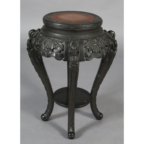 283 - A CHINESE CARVED WOOD URN STAND, circular with pierced foliate apron, on four serpentine legs joined... 