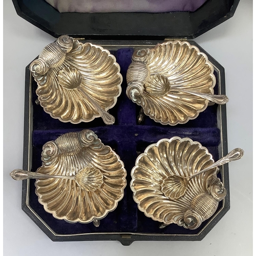 22 - A Victorian set of four EPNS shell-shaped salts, each on three dolphin feet and with matching spoon ... 