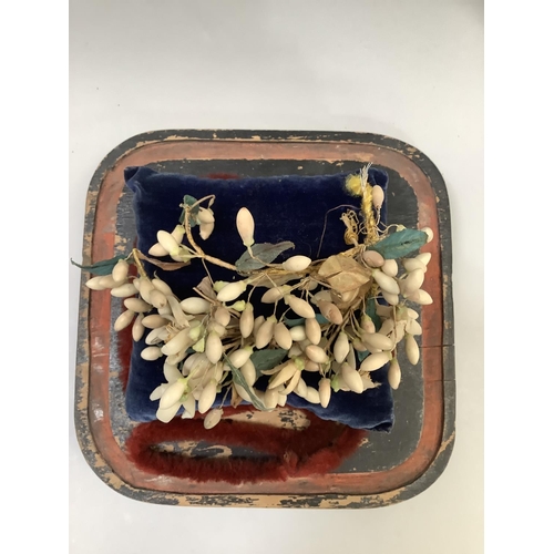 27 - A Victorian bride's wax and silk headdress displayed on a blue velvet cushion beneath a glass dome o... 