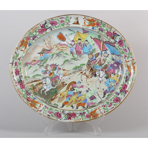 124 - A CHINESE CANTON FAMILLE ROSE CHARGER of oval outline, enamelled with a battle scene, warriors on ho... 