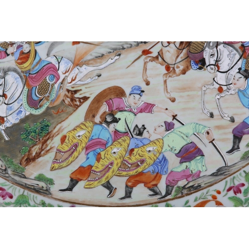124 - A CHINESE CANTON FAMILLE ROSE CHARGER of oval outline, enamelled with a battle scene, warriors on ho... 