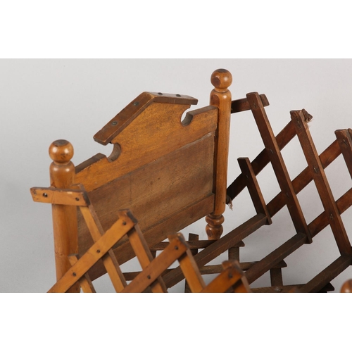 21 - A VICTORIAN DOLL'S BED in polished satin beech, having an arched head board and concertina frame, on... 