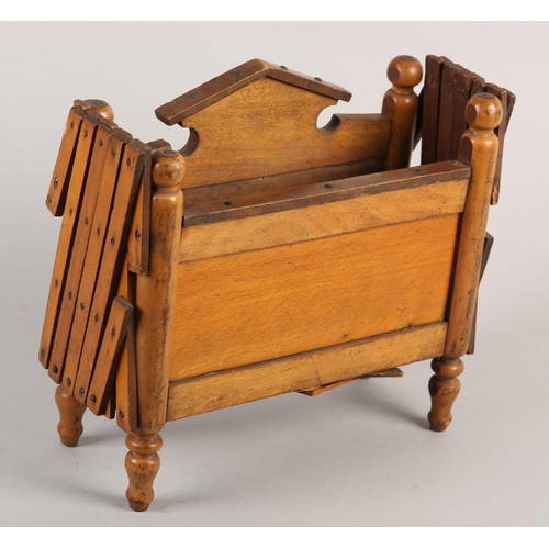 21 - A VICTORIAN DOLL'S BED in polished satin beech, having an arched head board and concertina frame, on... 