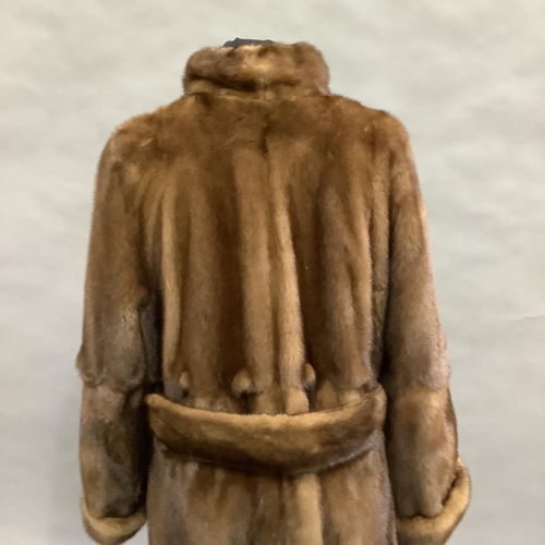 282 - A long length mink coat with stand-up collar and belt, Size 8 approximately