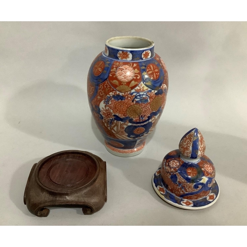 14 - A pair of Imari vases and domed covers with bud finials, overall height on stand 30cm