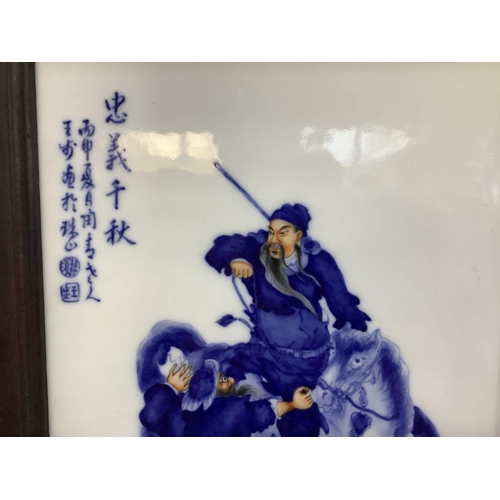 24 - A modern Chinese tile painted in blue and white highlighted in ochre depicting a horseman and swords... 