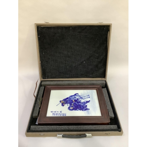 24 - A modern Chinese tile painted in blue and white highlighted in ochre depicting a horseman and swords... 
