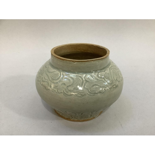 25 - A small celadon glaze earthenware pot with incised scroll decoration to the shoulder and stiff leaf ... 