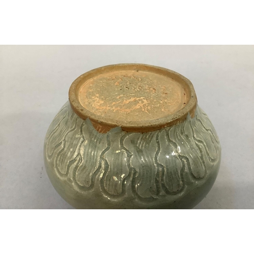 25 - A small celadon glaze earthenware pot with incised scroll decoration to the shoulder and stiff leaf ... 