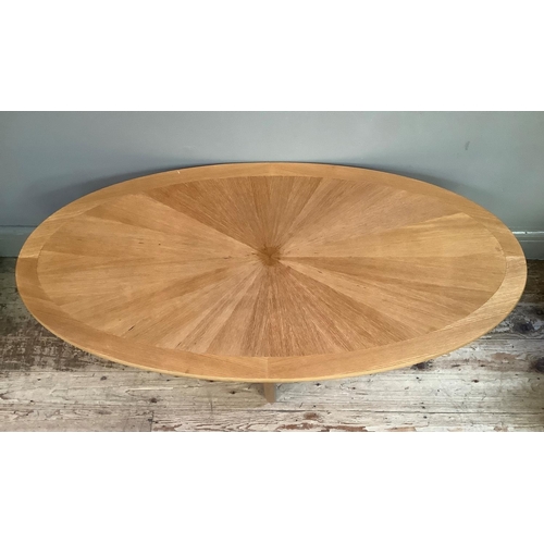 An oval teak coffee table of radiating veneers on four legs joined by ...