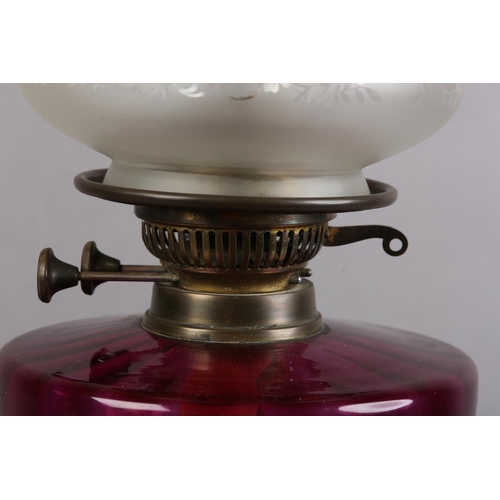 37 - A VICTORIAN BRASS OIL LAMP having an amethyst glass reservoir with amethyst tinted etched glass shad... 