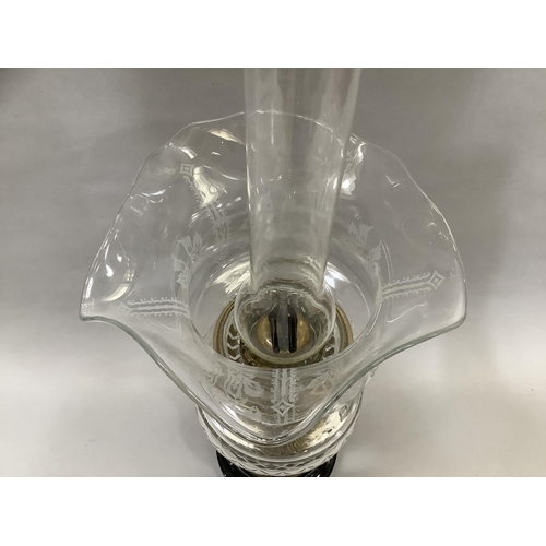 43 - A Victorian brass table lamp with cut glass reservoir, etched shade with deeply wavy rim and on a bl... 
