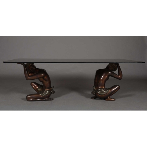 60 - A glass coffee table, rectangular, raised on two bronzed metal figures of crouching Nubian males, 15... 