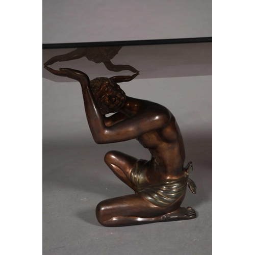 60 - A glass coffee table, rectangular, raised on two bronzed metal figures of crouching Nubian males, 15... 